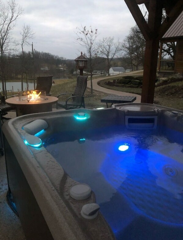 Un jacuzzi con luces LED azules, un brasero y mobiliario exterior.