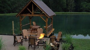 A wooden gazebo with a fire pit and seating area by a lake. - An Oasis indeed in Amish Country (Millersburg)