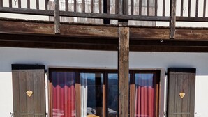 Un bâtiment en bois doté d’un balcon, d’un ensemble de portes doubles et d’un sol recouvert de neige.