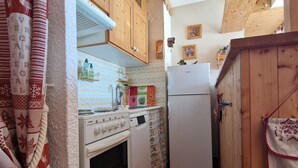 Une cuisine de taille réduite, avec des meubles de rangement en bois, une cuisinière blanche et un réfrigérateur.