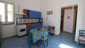 A compact kitchen with a dining table, chairs, and a small cabinet. - Casa Al Mar Canneto Via Mazzini (Lipari)