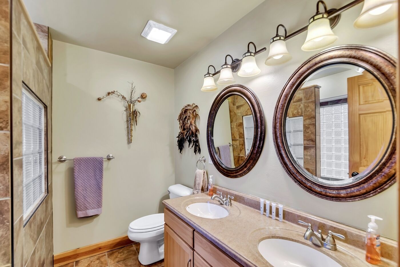 A bathroom with two sinks, a toilet, and two large mirrors.