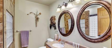 A bathroom with two sinks, a toilet, and two large mirrors.