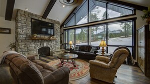 Un salón espacioso con chimenea de piedra, ventanas amplias y una zona de estar acogedora.