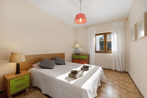 Una camera da letto con un letto, comodini, una lampada, una finestra con tende e una lampada a parete.