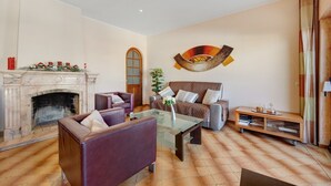 A living room with a fireplace, a sofa, a coffee table, and a wall-mounted artwork. - Apartment 'Lagos Terrace Villa' with Private Terrace, Wi-Fi and Air Conditioning (Lagos)