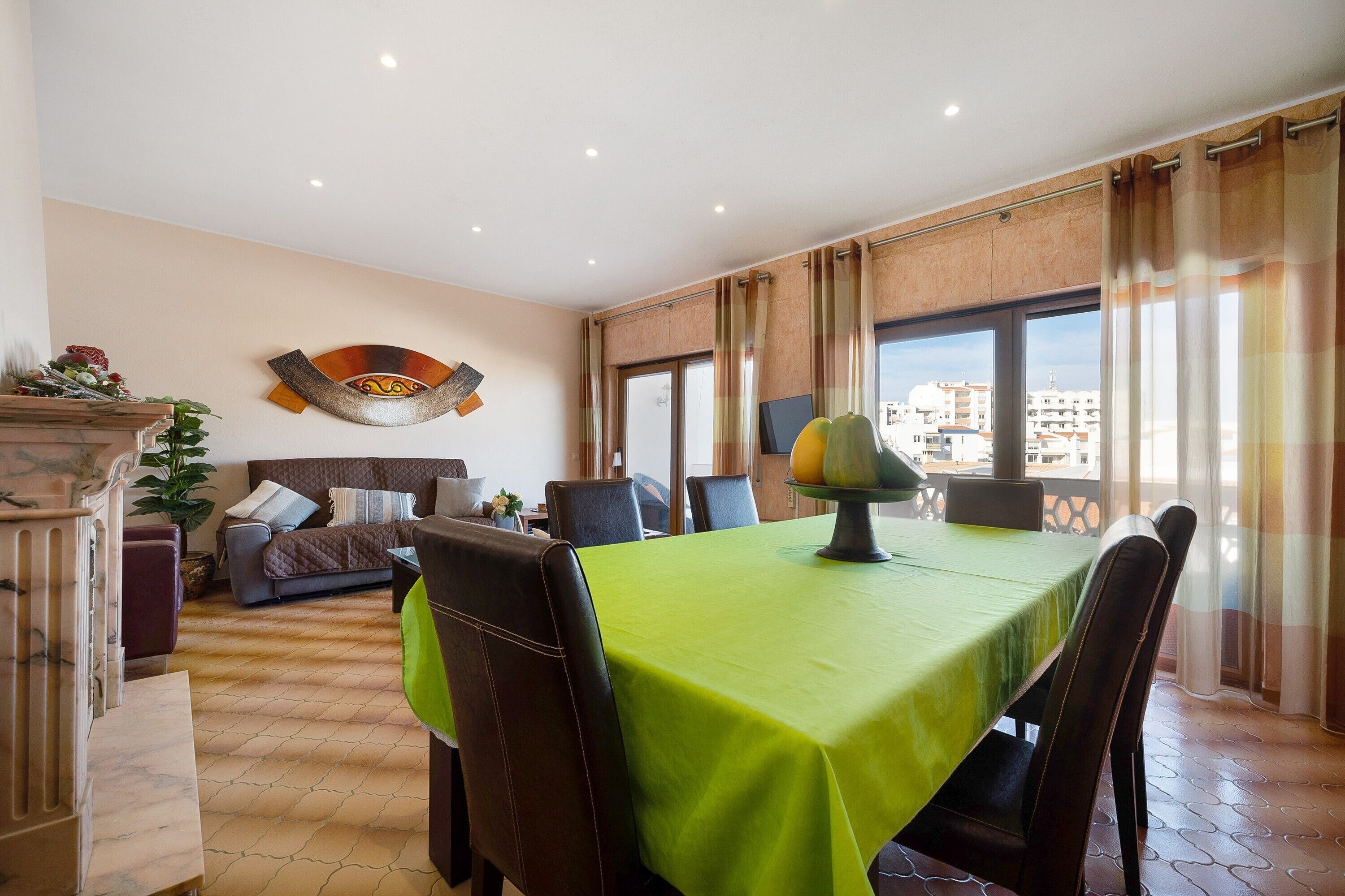 A dining area with a table set for four, a sofa, and a decorative wall piece.