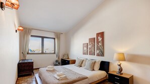 A bedroom with a large bed, a bedside table, a nightstand, a window with curtains, and wall art. - Apartment 'Lagos Terrace Villa' with Private Terrace, Wi-Fi and Air Conditioning (Lagos)