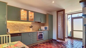 A kitchen with green cabinets, a microwave, and a brick-patterned floor.