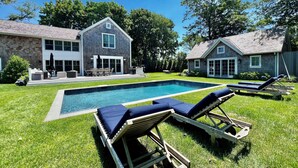 Ein Garten mit Swimmingpool, zwei Liegestühlen und einer Terrasse mit Gartenmöbeln.