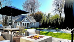 Eine Terrasse mit Gartenmöbeln, einem Feuerkorb und einem Swimmingpool.
