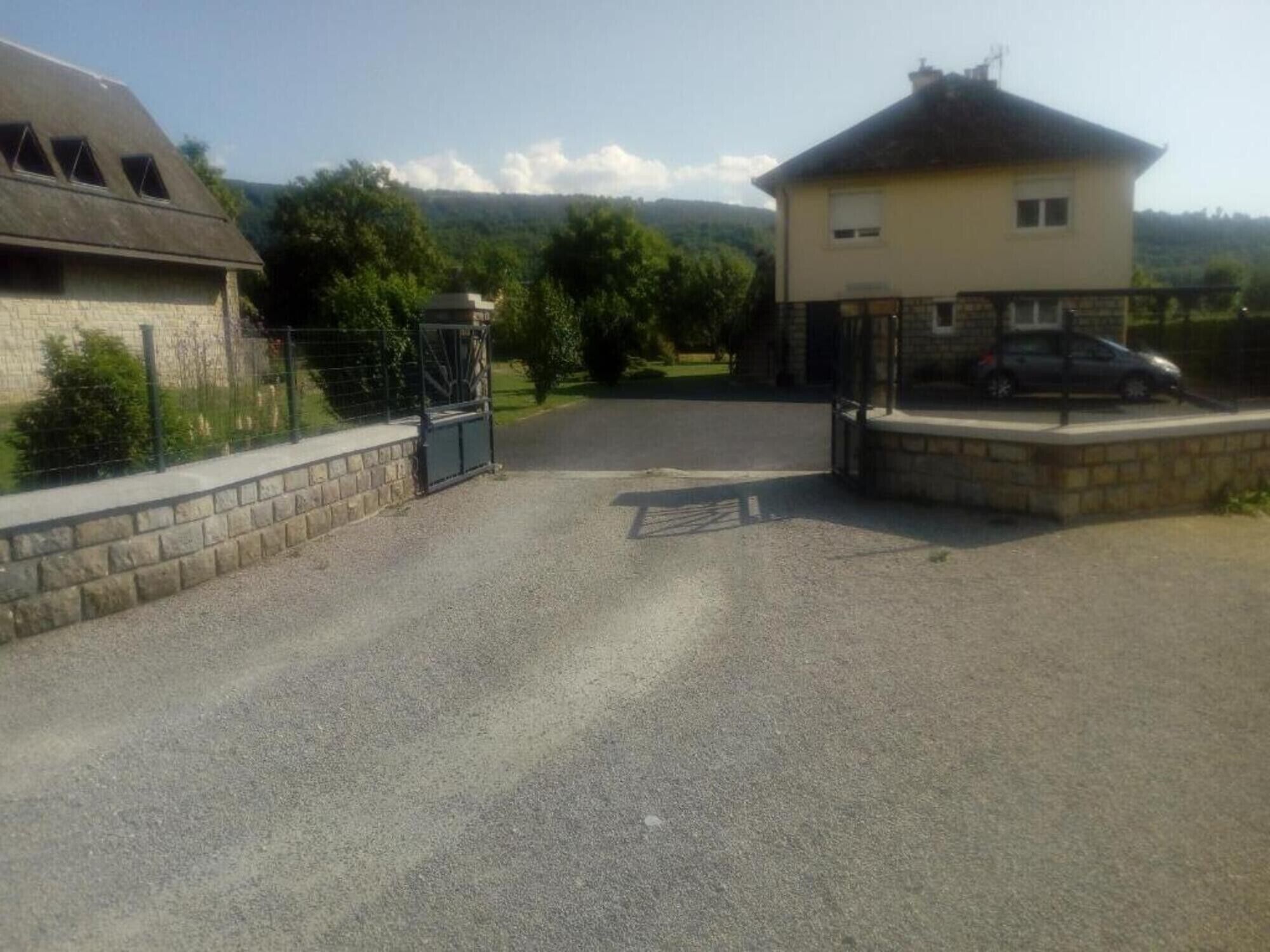 A gravel driveway leading to a gated entrance with a parked car.