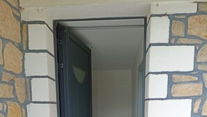 Une porte qui donne sur un couloir, avec un mur de pierre d’un côté et un mur uni de l’autre.