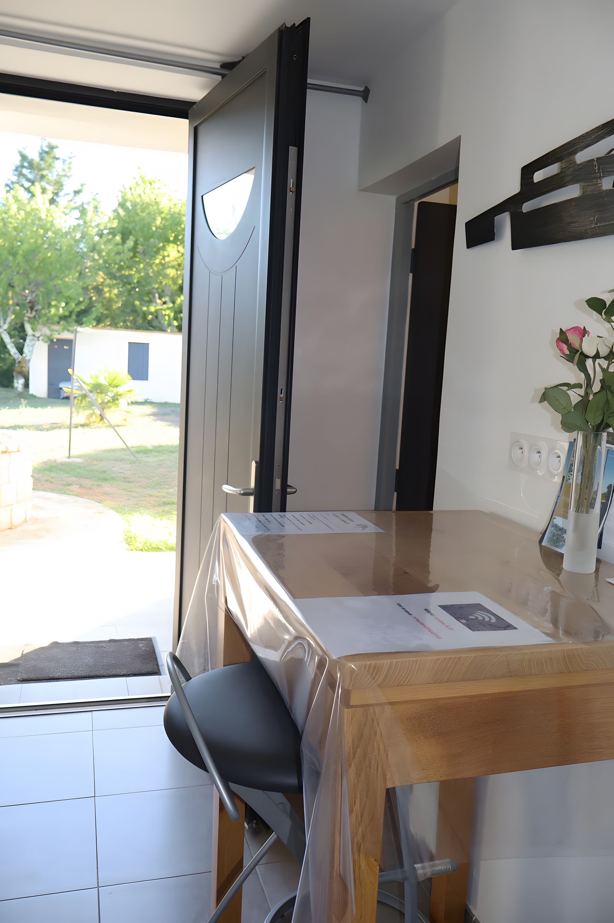 Une pièce avec une table en bois, une chaise, une porte et une vue sur l’extérieur.