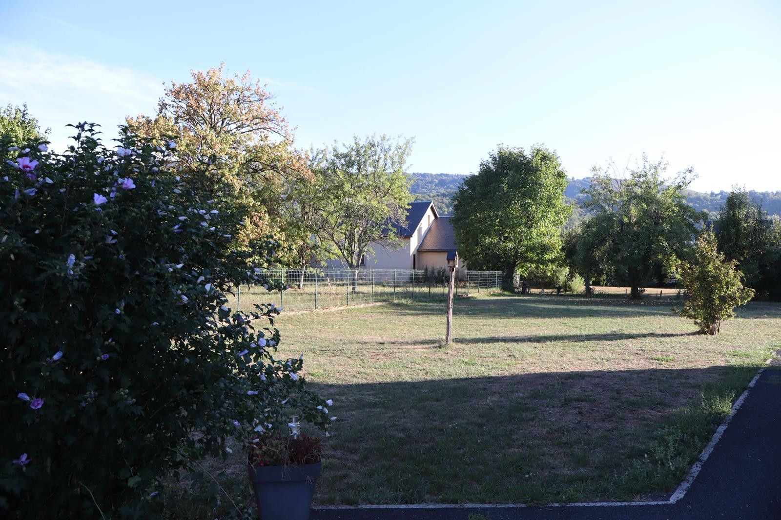Ein Wohngebiet mit einem Haus, einem eingezäunten Garten und blauem Himmel.