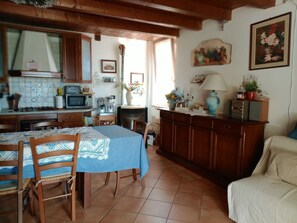 A cozy kitchen with a dining table, chairs, and a sofa.
