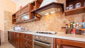 A kitchen with wooden cabinets, a stove, oven, and various kitchen items on the countertop.