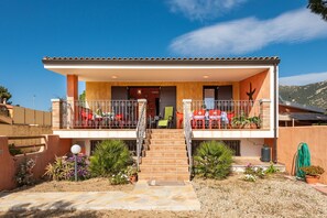 Une maison à deux étages avec un balcon, un escalier et un jardin.