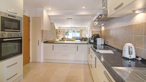 Een moderne keuken met inbouwapparatuur, een centraal eiland en uitzicht op de woonkamer.