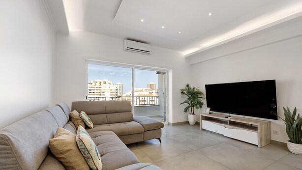 A modern living room with a sofa, TV, and potted plants. - Holiday Apartment 'Mar E Sol' with Balcony & Wi-Fi (Portimão)
