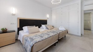 A bedroom with two beds, a dresser, a nightstand, a potted plant, and a walk-in closet. - Holiday Apartment 'Mar E Sol' with Balcony & Wi-Fi (Portimão)