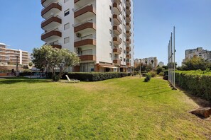 Un immeuble résidentiel à plusieurs étages, doté de balcons, d’une pelouse bien entretenue et surplombant un ciel dégagé.