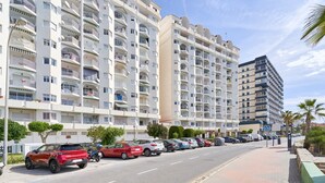 A multi-story residential building with balconies, parked cars, and a clear sky. - Apartment 'With Garage In Almuñecar' with Sea View, Wi-Fi and Air Conditioning (Almunecar)