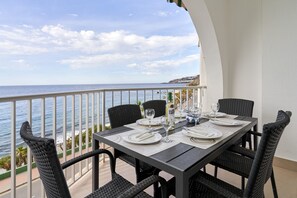 Une table à manger dressée pour quatre personnes, avec vue sur l’océan.