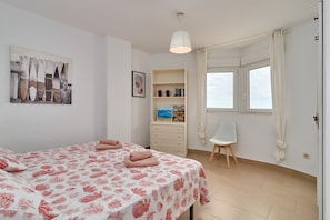 A bedroom with a bed, a bookshelf, a chair, and a window.