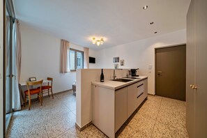 Cozinha compacta com pia, bancada e área de refeições com cadeiras.