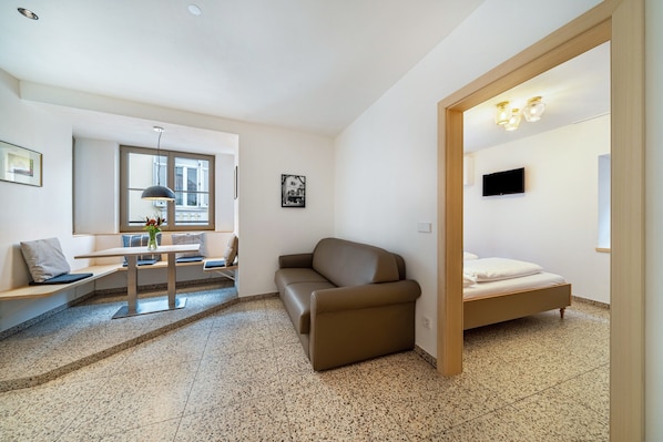 A modern room with a sofa, a bed, a dining table, and a TV.