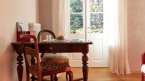 Una mesa de madera con una silla, una ventana con cortinas y una puerta.
