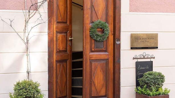Una puerta doble de madera con un adorno de guirnalda, una placa y un letrero.