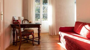 Una habitación con una mesa de comedor de madera, un sofá rojo y una ventana con cortinas.