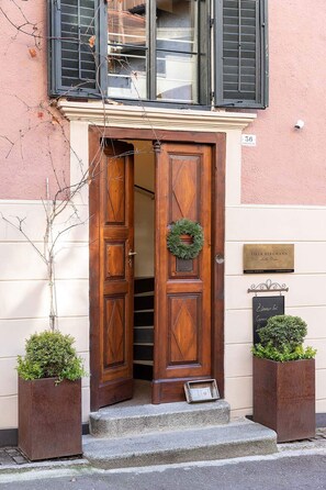 Une porte à deux battants en bois, ornée d’une guirlande, d’une plaque et d’une enseigne.