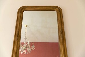 Un miroir avec un cadre doré qui reflète un lustre.