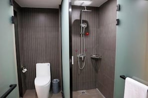 A compact bathroom with a toilet, a shower with a handheld showerhead, and a trash bin. - Junyi Hotel (Huaibin Mobile Building Store) (Huaibin)