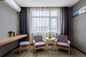 A small, modern room with a desk, two chairs, a small table, and a window with curtains. - Junyi Hotel (Huaibin Mobile Building Store) (Huaibin)