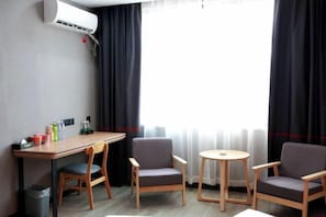 A hotel room with a desk, two chairs, a small table, and a window with curtains. - Junyi Hotel (Huaibin Mobile Building Store) (Huaibin)