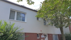 Een woongebouw met twee verdiepingen, een witte gevel en een rood bakstenen grondstuk.