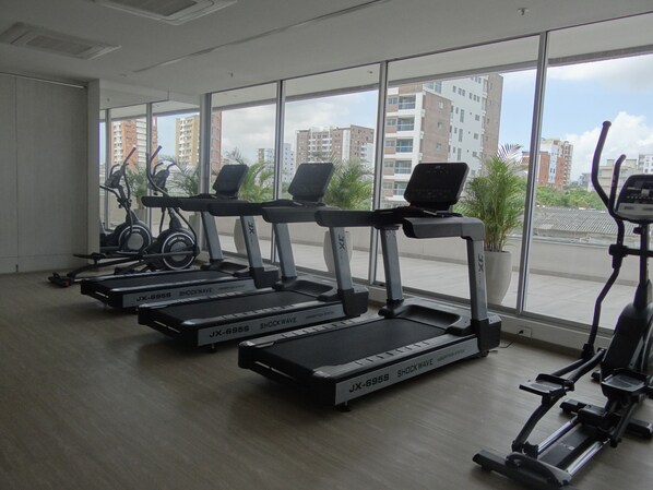 A gym with treadmills, stationary bikes, and a rowing machine. - Distrito 90 by Wellcome (Barranquilla)