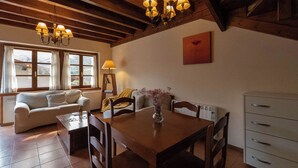 A cozy living room with a wooden dining table, a sofa, and a fireplace. - RURAL HOUSE WITH VIEWS OF THE GREEN ASTURIAN MOUNTAINS (Pola de Lena)