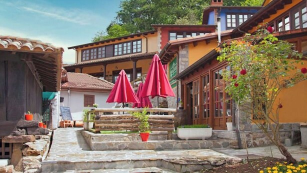 A courtyard with stone steps, red umbrellas, and traditional buildings with wooden balconies. - RURAL HOUSE WITH VIEWS OF THE GREEN ASTURIAN MOUNTAINS (Pola de Lena)