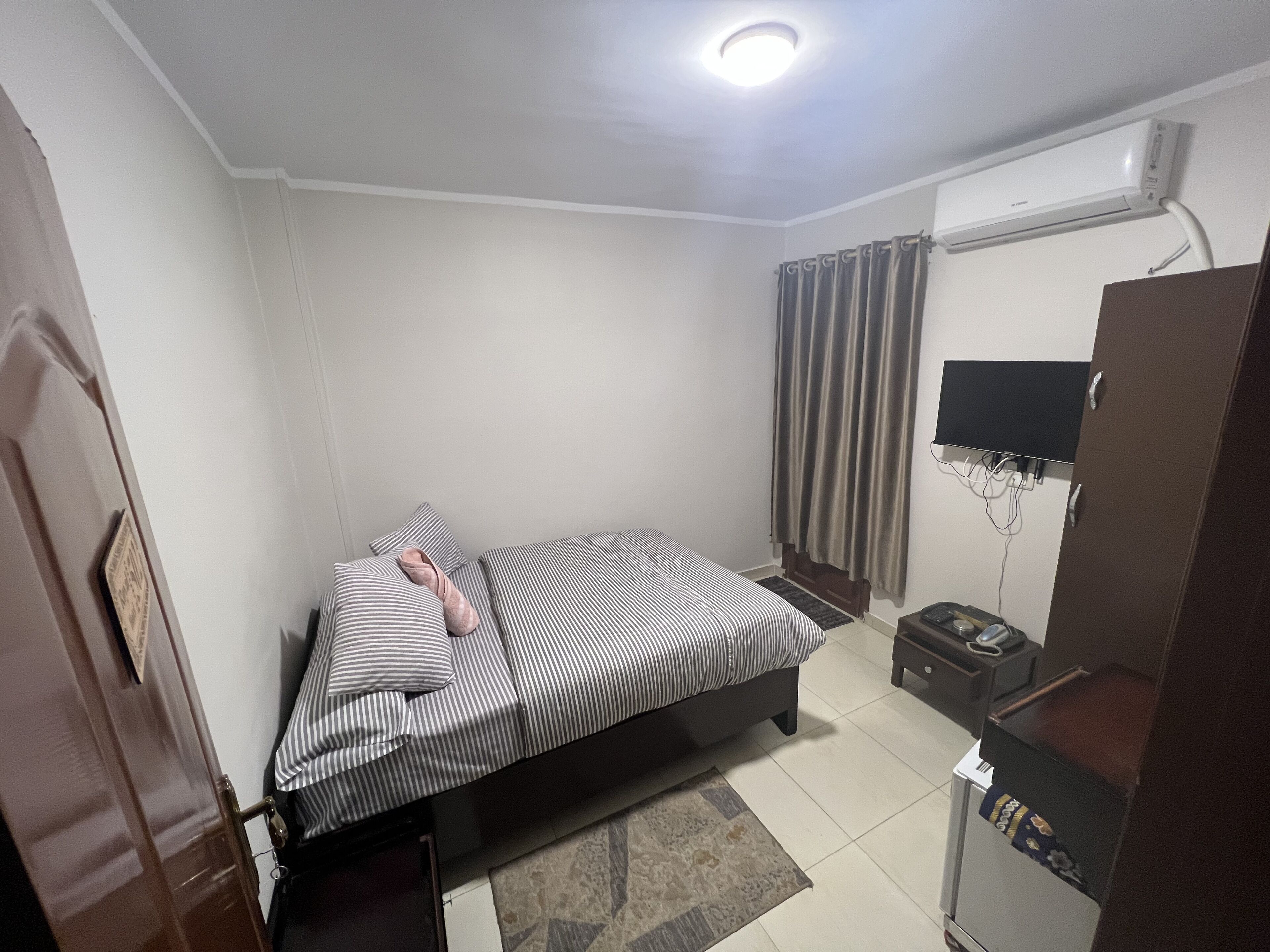 A bedroom with a bed, a TV, a desk, and a wardrobe.