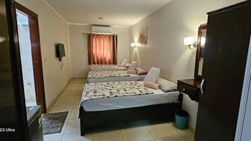 Une chambre d’hôtel avec deux lits, un bureau, un miroir et une télévision.