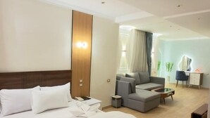 A hotel room with a large bed, a sofa, a desk, and a chair. - Royal hotel tanta (Tanta)