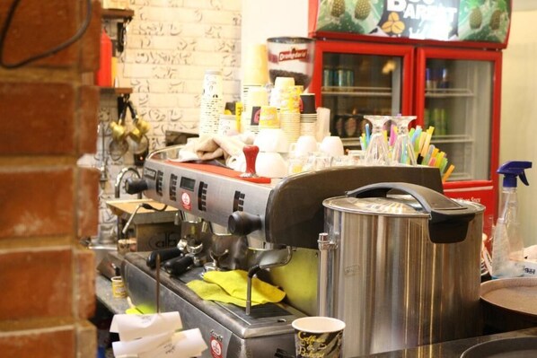 A coffee machine with a stainless steel pot, stacked cups, and a window with a red frame. - Royal hotel tanta (Tanta)