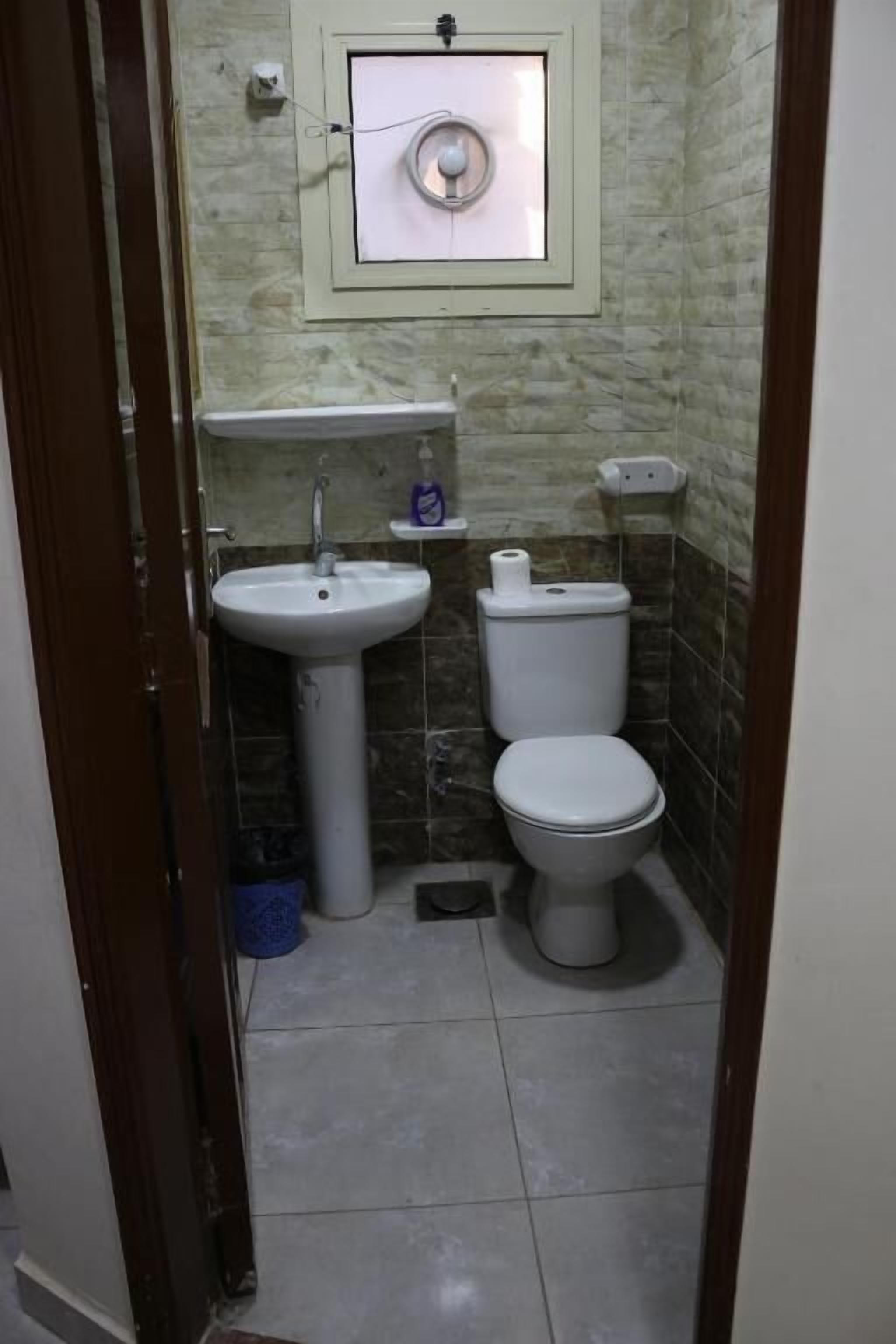 A small bathroom with a sink, toilet, and a wall-mounted light fixture.