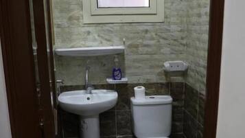 A small bathroom with a sink, toilet, and a wall-mounted light fixture.