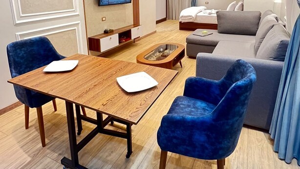 A modern hotel room with a dining area, a sofa, a TV, and a bed. - Royal hotel tanta (Tanta)